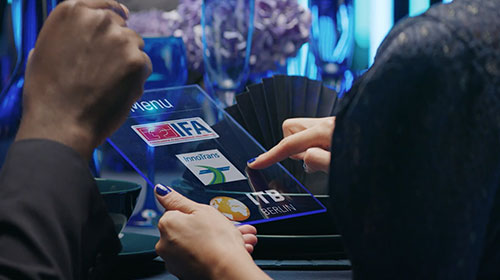 Eine Hand hält ein Tablet, auf dem die Logos wichtiger Berliner Messen zu sehen sind